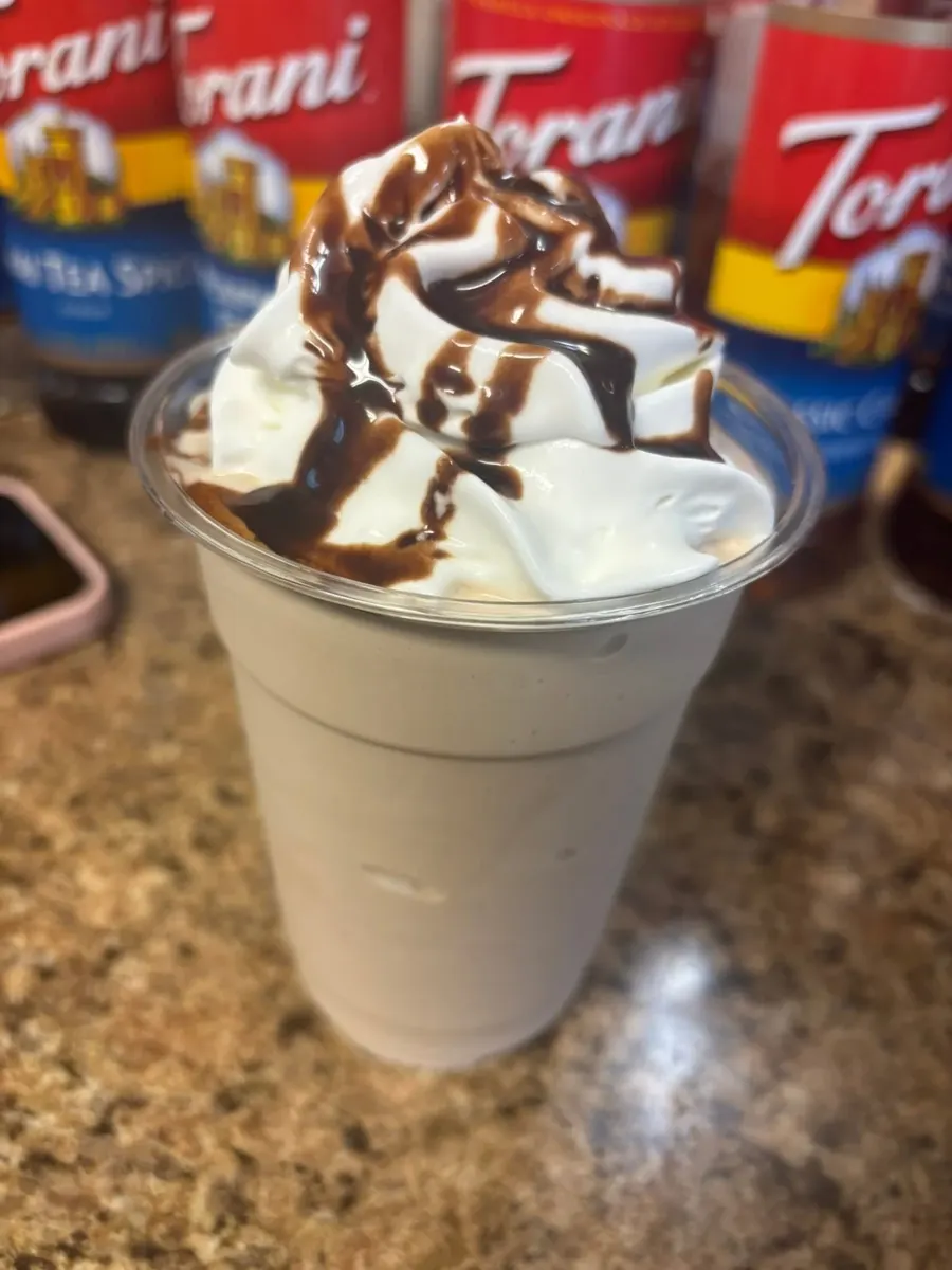 Frappe topped with whipped cream and chocolate drizzle